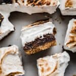 S'mores Brownies with a toasted homemade marshmallow cream and graham cracker crust on a white surface background.