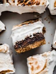 S'mores Brownies with a toasted homemade marshmallow cream and graham cracker crust on a white surface background.