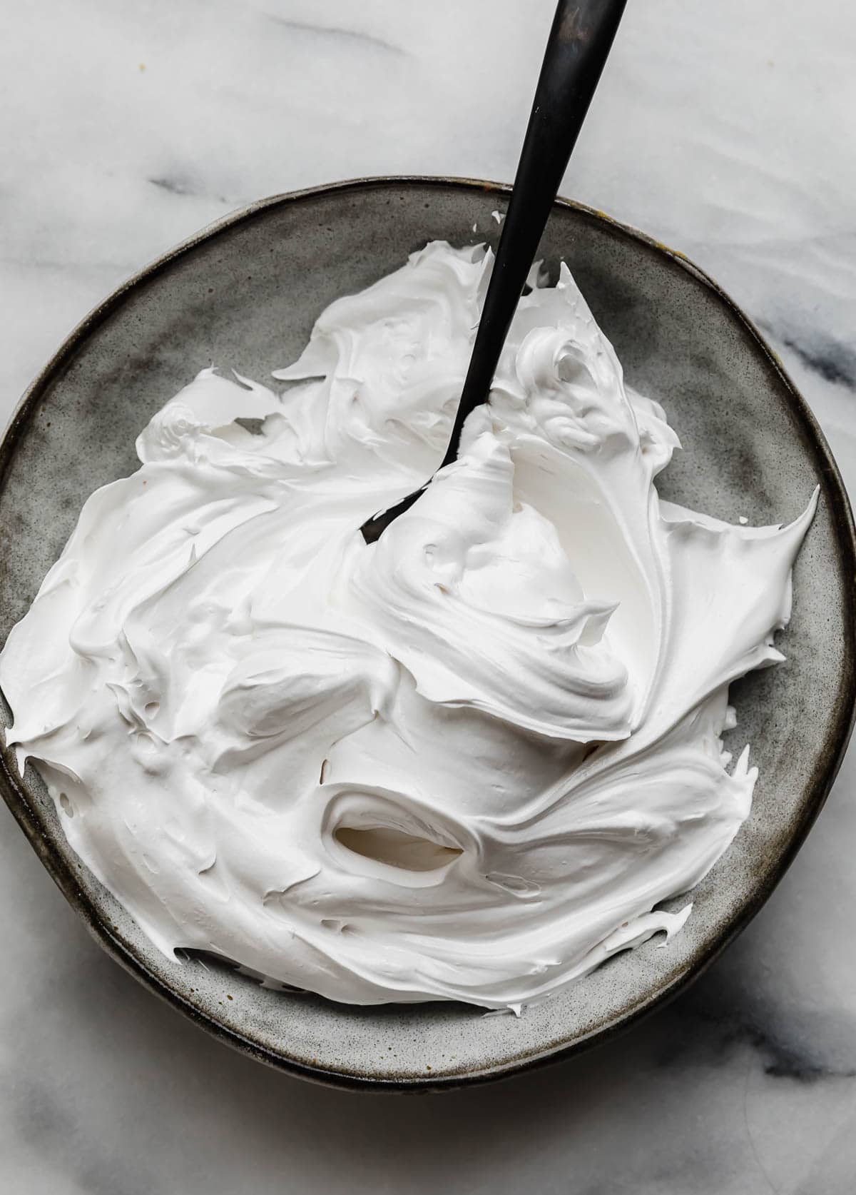 Homemade Marshmallow Cream fluffed into swirls on a gray plate. 