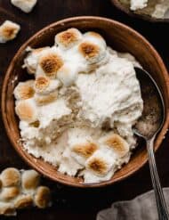 Toasted Marshmallow Frosting made with real toasted marshmallows, in a brown bowl on a dark brown surface.