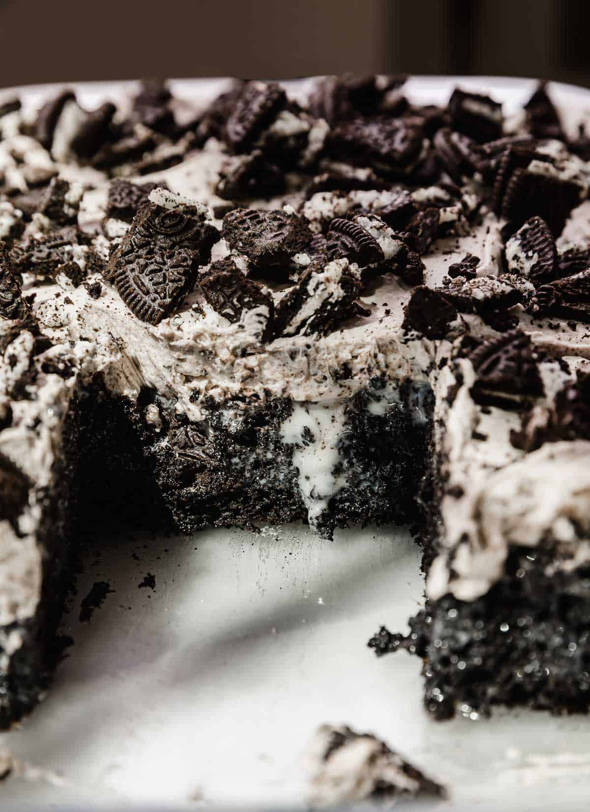 An Oreo Poke Cake oozing with sweetened condensed milk, and topped with Oreo frosting and crushed Oreos.