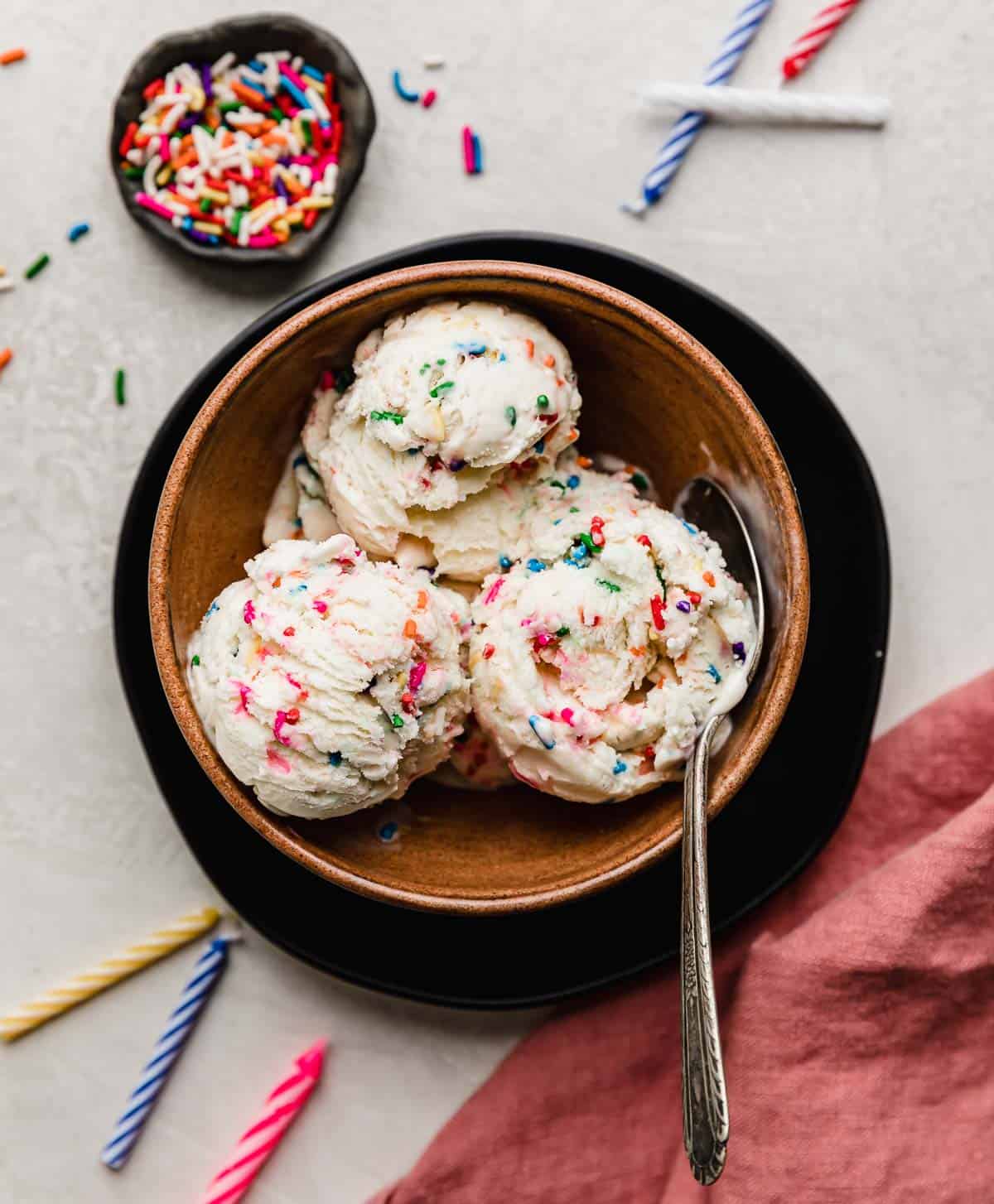 Sprinkle ice cream with cake mix scooped into a brown bowl on a white background.