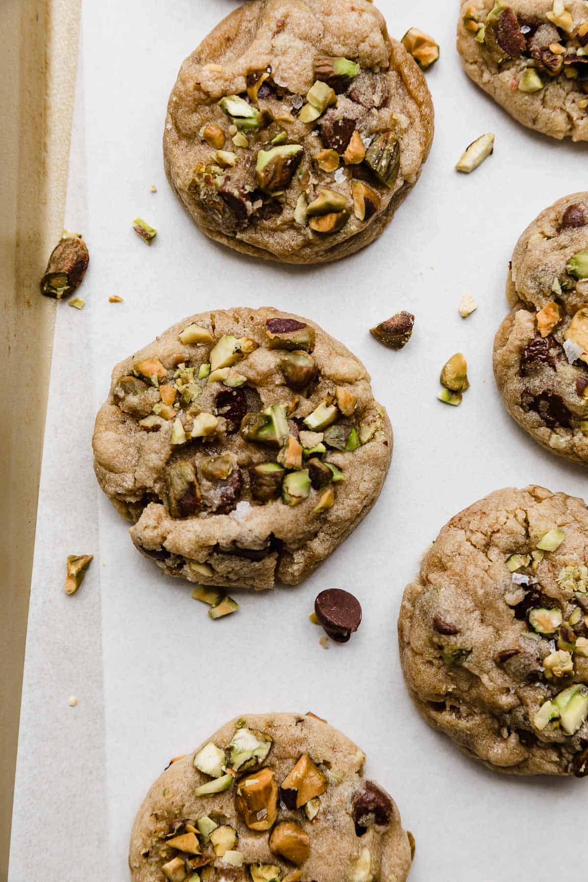 Chocolate Chip and Pistachio Cookies on a white parchment paper.