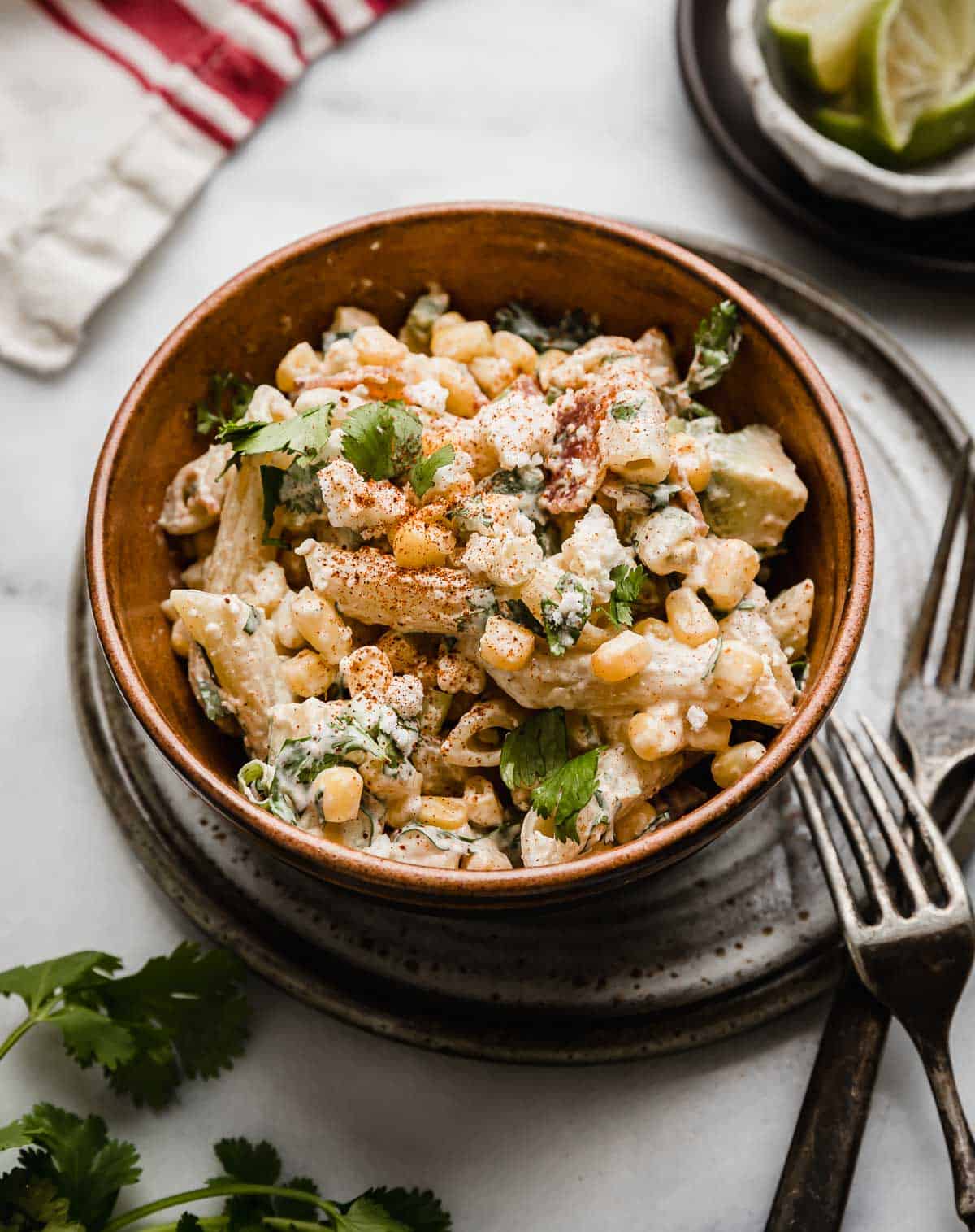 Mexican Street Corn Pasta Salad recipe in a brown bowl with two forks next to the bowl.