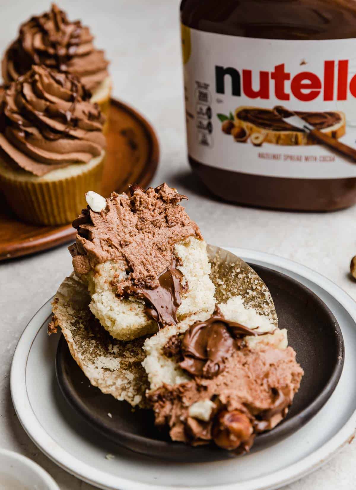 A Nutella Cupcake on a black plate cut in half, showing the inside filled with Nutella.