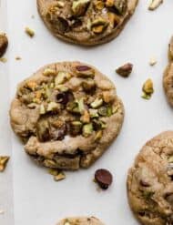 Chocolate Chip and Pistachio Cookies on a white parchment paper.