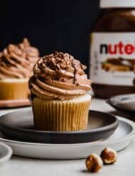 A Nutella Cupcake on a black plate with a Nutella jar in the background.