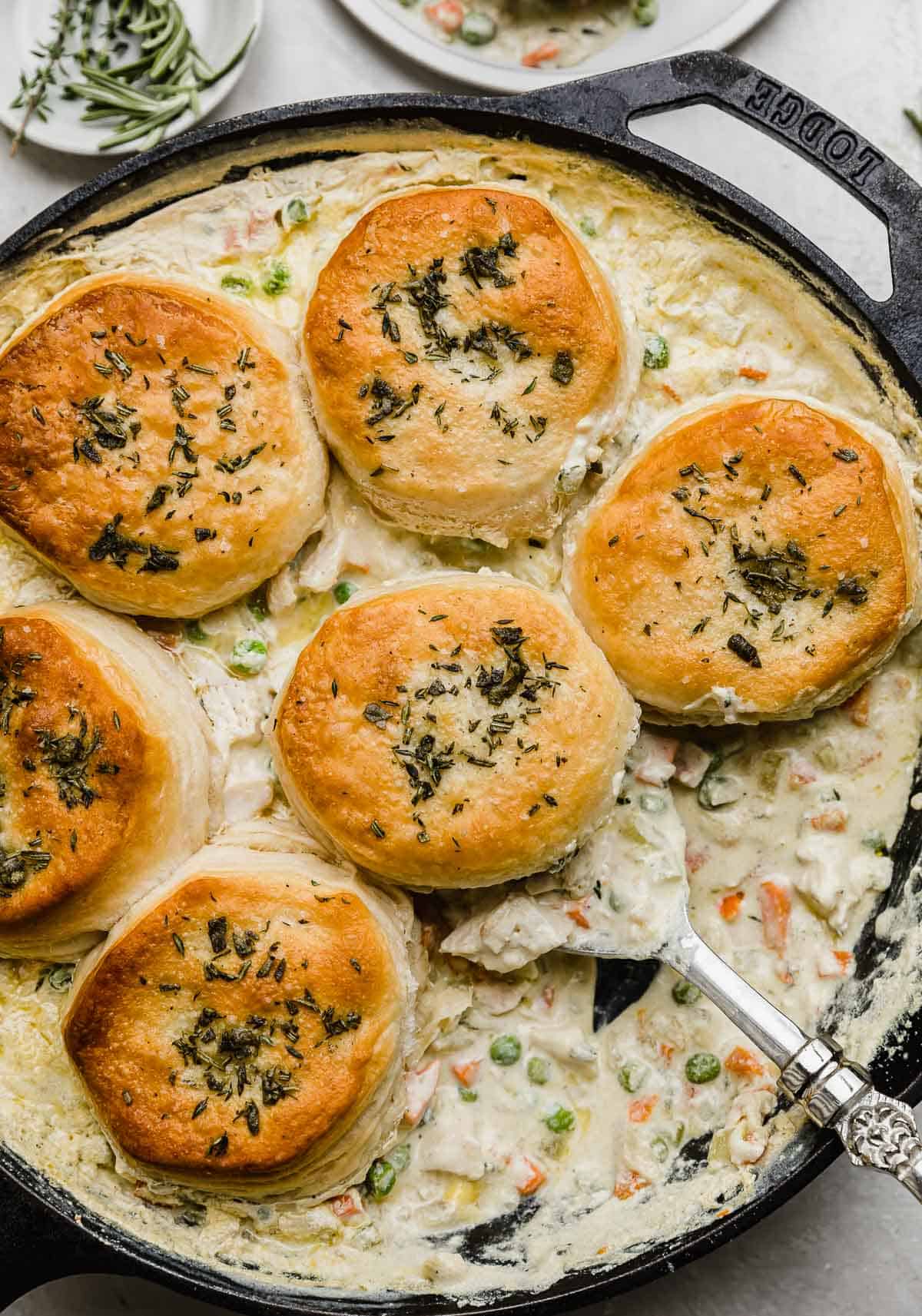 Overhead photo of Cast Iron Chicken Pot Pie with a serving spoon scooping up a center biscuit.