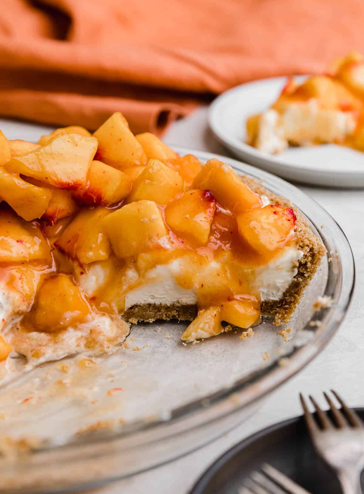 A Peach Cream Pie made with cream cheese base layer on a graham cracker crust and topped with chopped fresh peaches.