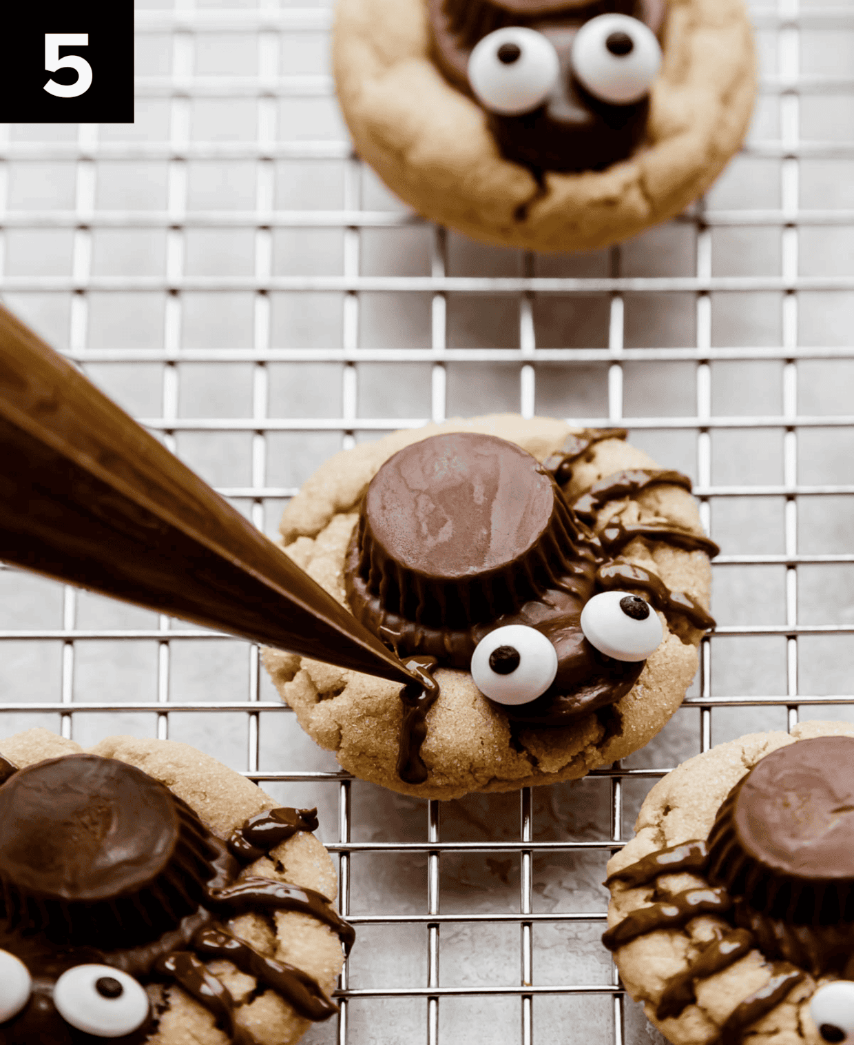 Melted chocolate being piped into 8 spider legs on a Halloween peanut butter spider cookie.