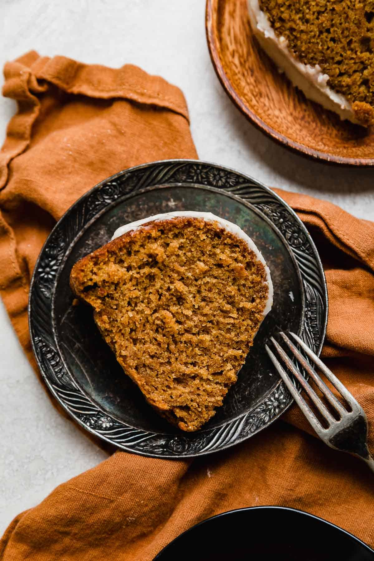 The best pumpkin bundt cake slice on a vintage plate that's on an orange linen napkin.