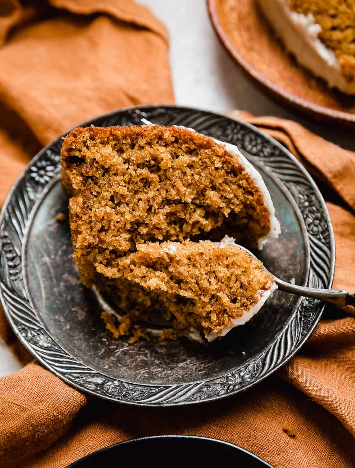 A slice of Pumpkin Bundt Cake on a vintage plate with a fork cutting into the pumpkin cake.