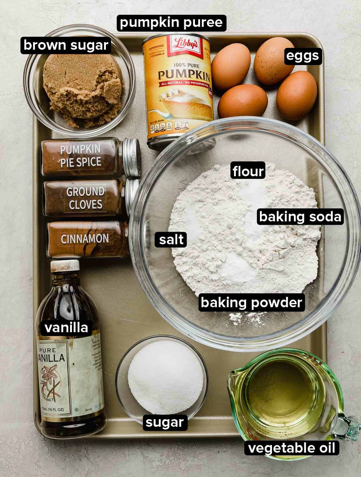 Moist Pumpkin Bundt Cake recipe ingredients portioned into some glass bowls on a silver baking sheet.