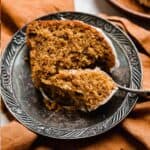 A slice of Pumpkin Bundt Cake on a vintage plate with a fork cutting into the pumpkin cake.