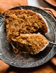 A slice of Pumpkin Bundt Cake on a vintage plate with a fork cutting into the pumpkin cake.