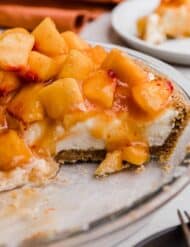 A Peach Cream Pie made with cream cheese base layer on a graham cracker crust and topped with chopped fresh peaches.