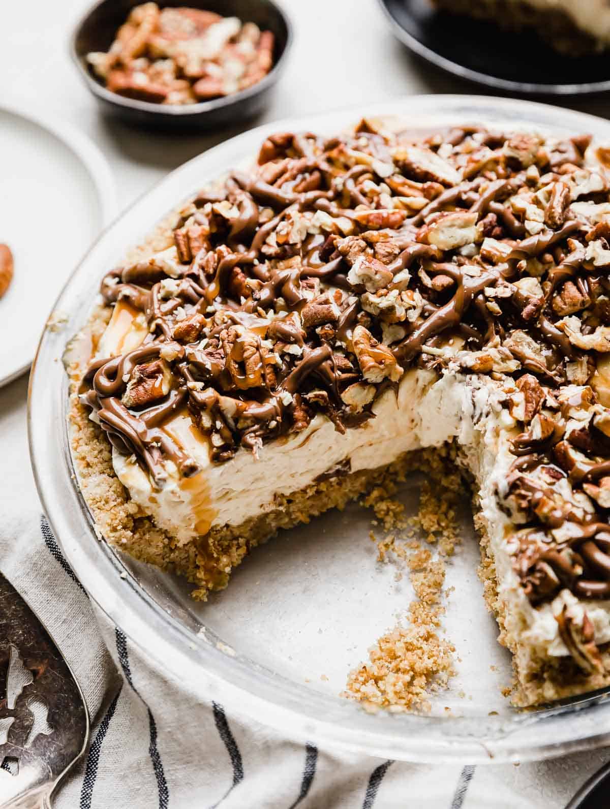 A Turtle Pie recipe in a 9" pie plate with a pecan graham cracker crust, caramel cheesecake layer and chocolate caramel and pecan topping.