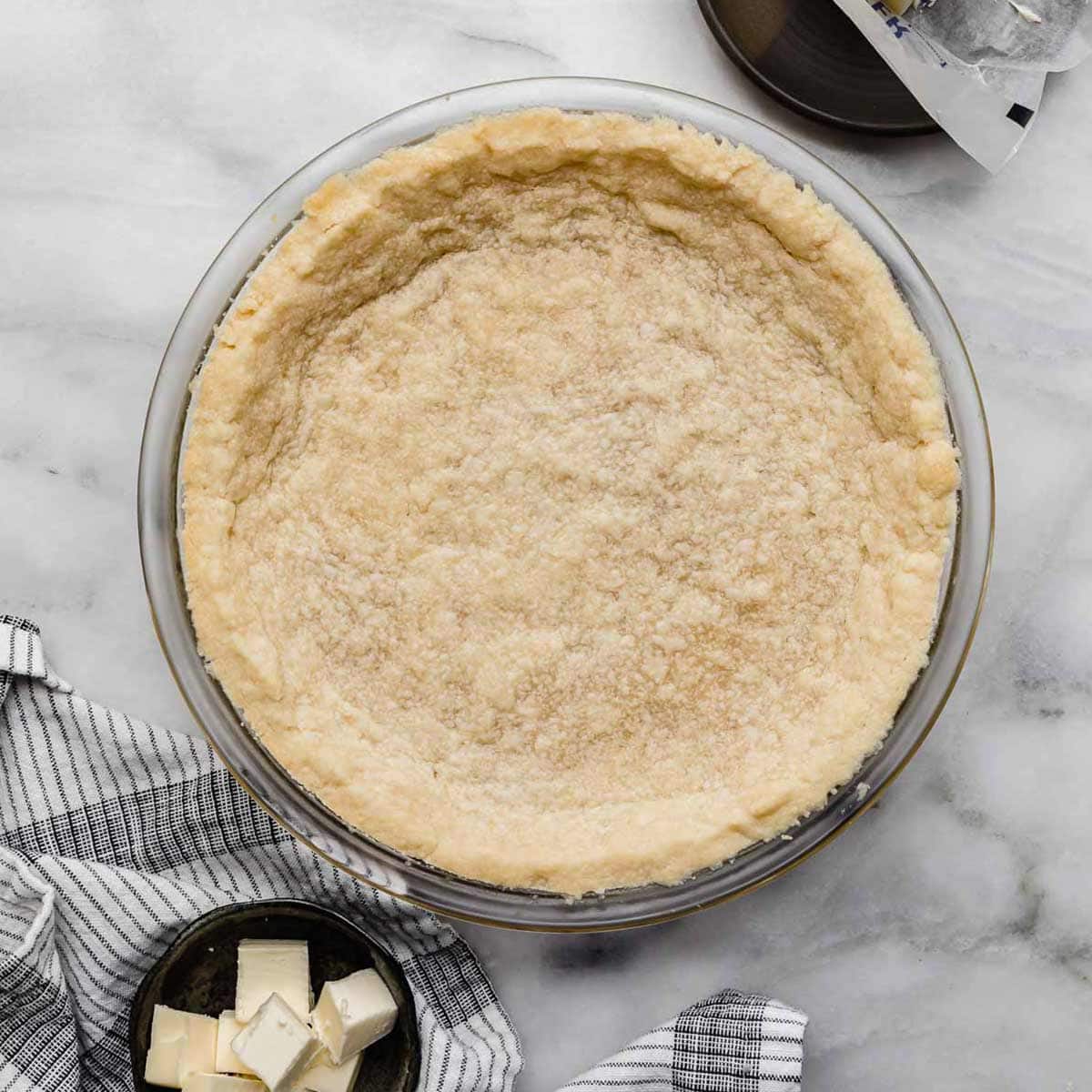 Shortbread Pie Crust baked in a 9" round pie plate on a light gray marbled surface.