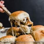 Cheesy Philly Cheesesteak Slider on a hawaiian roll balancing on a metal spatula.