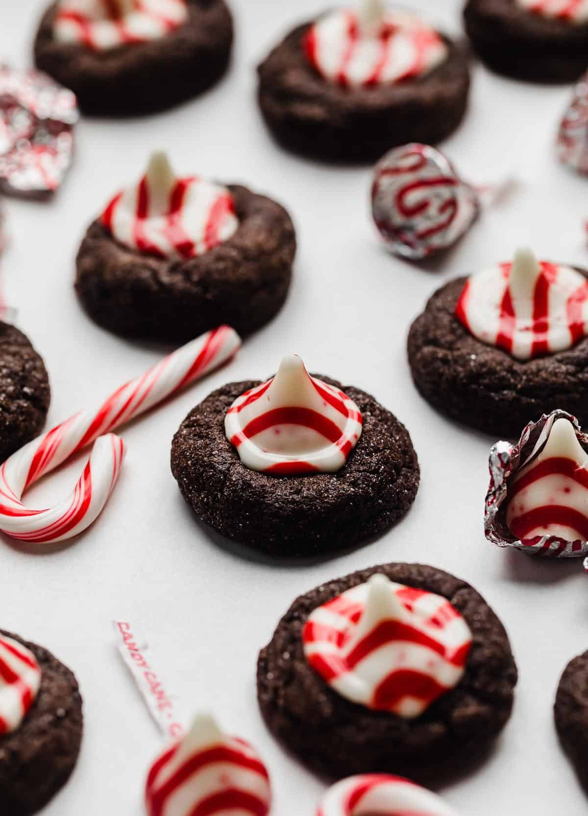 Chocolate Peppermint Blossoms cookies topped with a candy cane kiss on a white background.