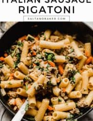 A close up photo of cooked sausage mixed with rigatoni noodles, carrots, spinach, and array of spices in a creamy sauce.