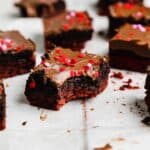 A chocolate covered red velvet brownie topped with Oreo truffle with a bite taken out of the Valentines inspired brownie.