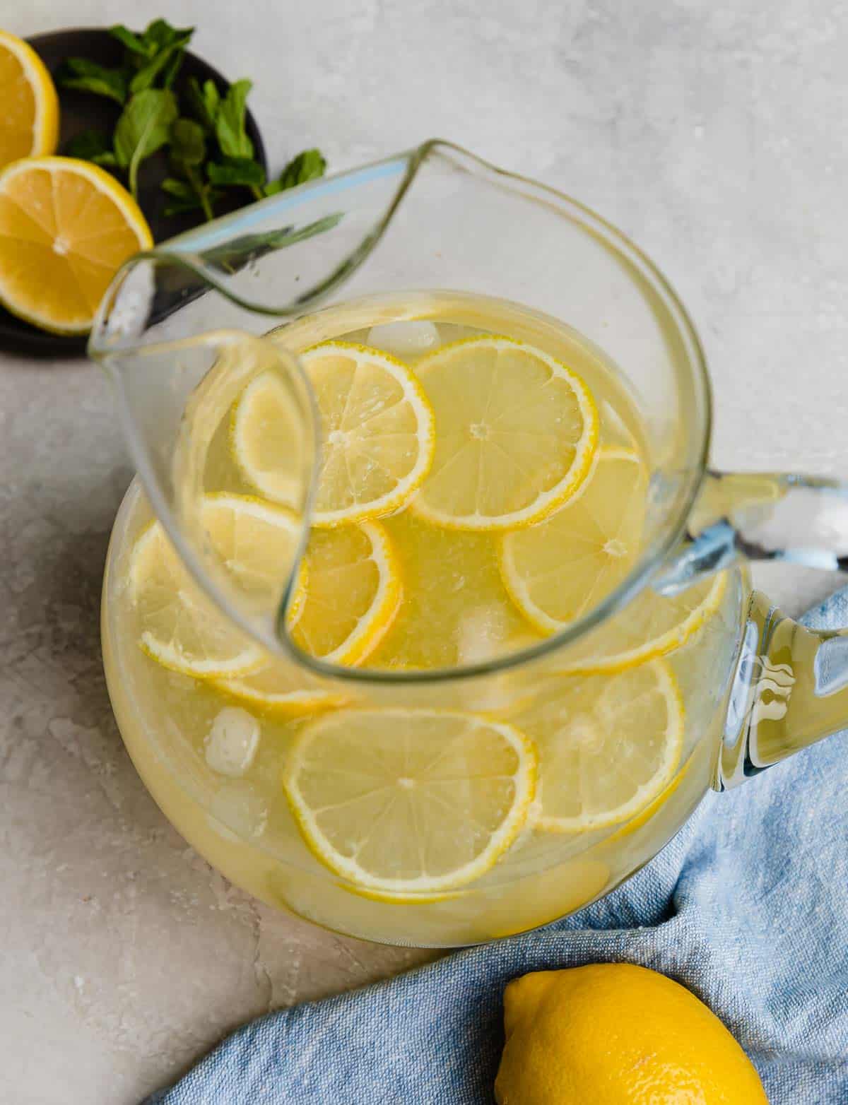 Freshly squeezed lemonade in a glass pitcher with lemon slices in the pitcher.