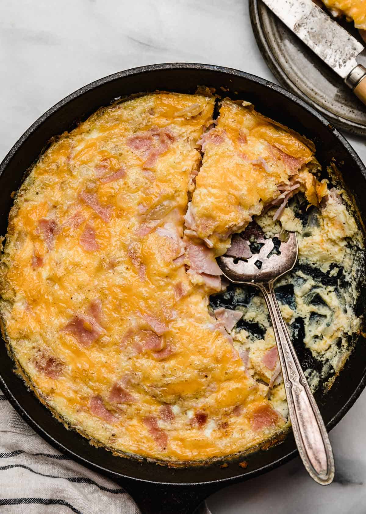 Overhead photo of a Ham and Cheese Frittata cut into triangles with several pieces missing from the cast iron skillet.