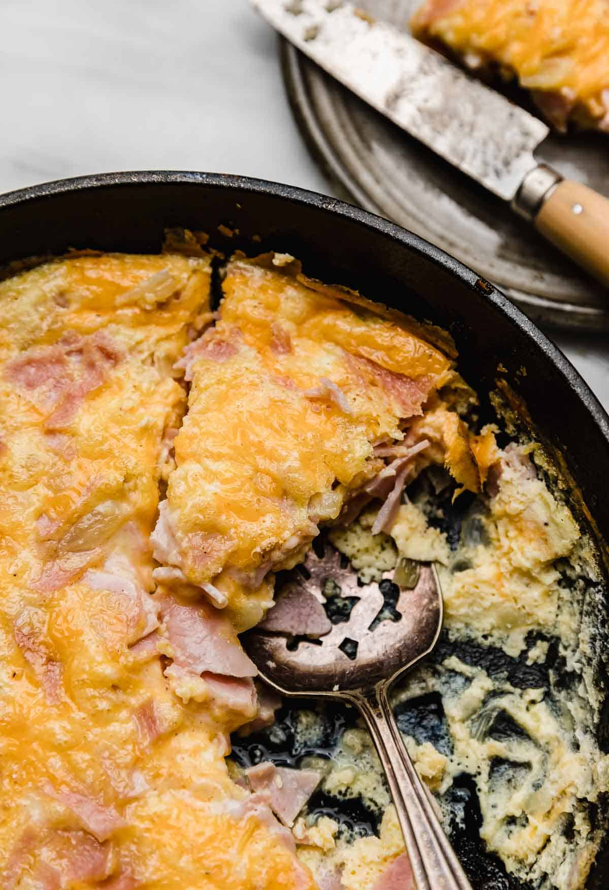 Ham and Cheese Frittata in a cast iron pan cut into triangles.