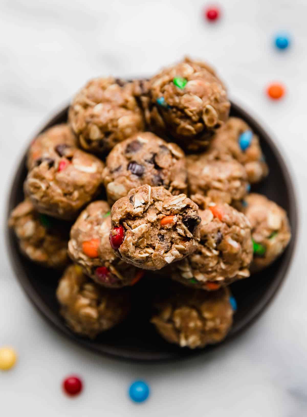 Overhead photo of Monster Cookie Protein Balls on a black plate on a white surface.