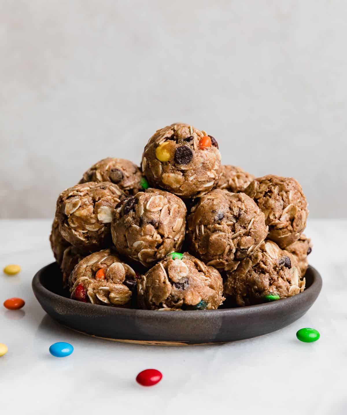 A stack of Monster Cookie Protein Balls on a black plate against a white background.
