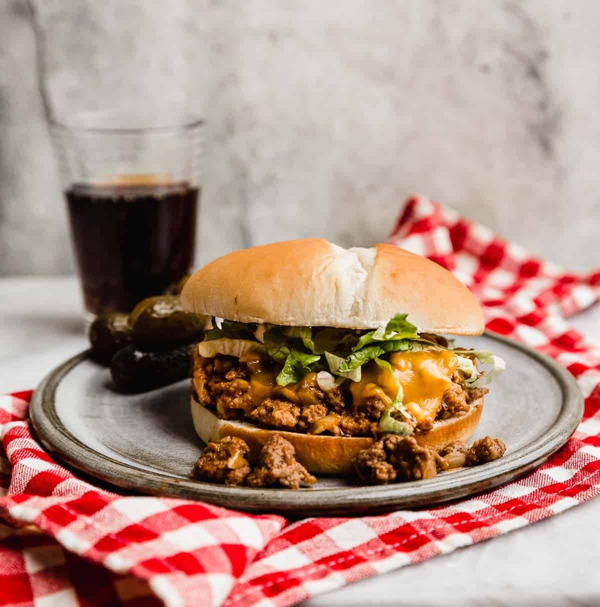 A Cheeseburger Sloppy Joe on a grey plate with melted cheese and shredded lettuce overtop of the sloppy Joe mixture.