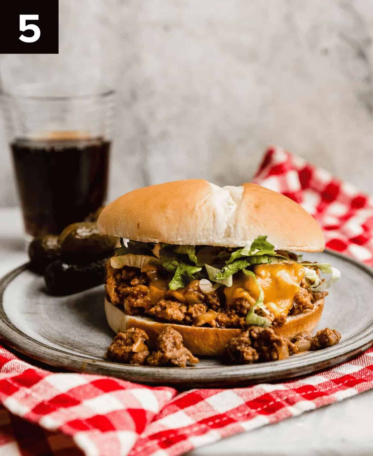 A finished Cheeseburger Sloppy Joe on a gray plate against a gray background.