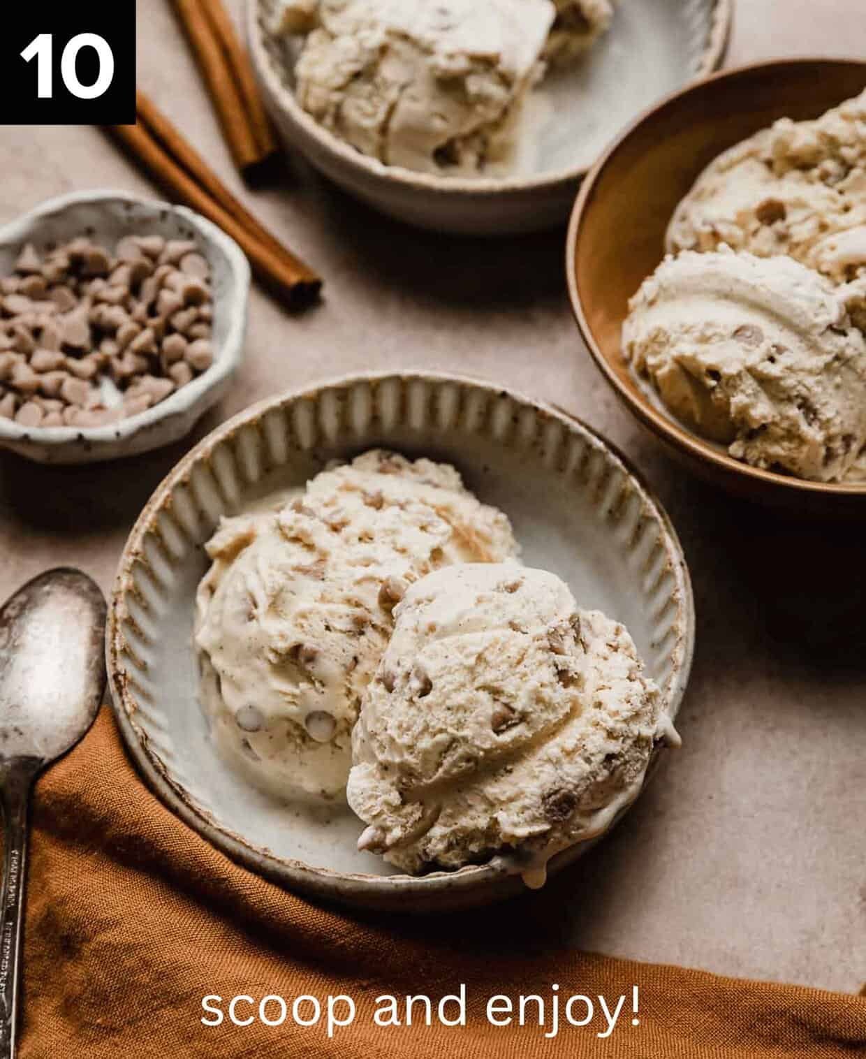 Scoops of homemade Cinnamon Ice Cream in a tan bowl surrounded by a small bowl of mini cinnamon chips and an additional bowl of homemade Cinnamon Ice Cream.