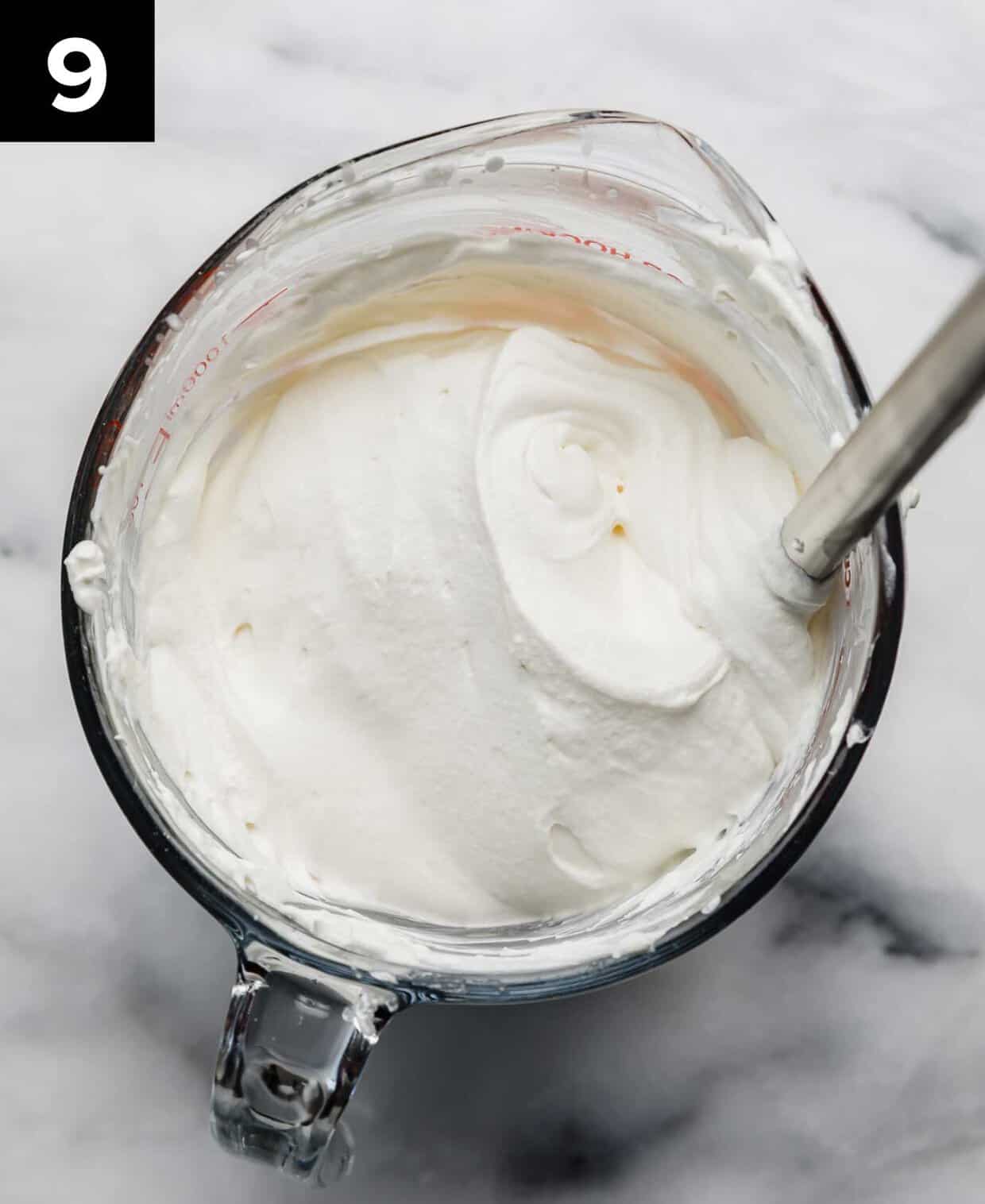 Freshly whipped billowy whipped cream in a glass bowl.