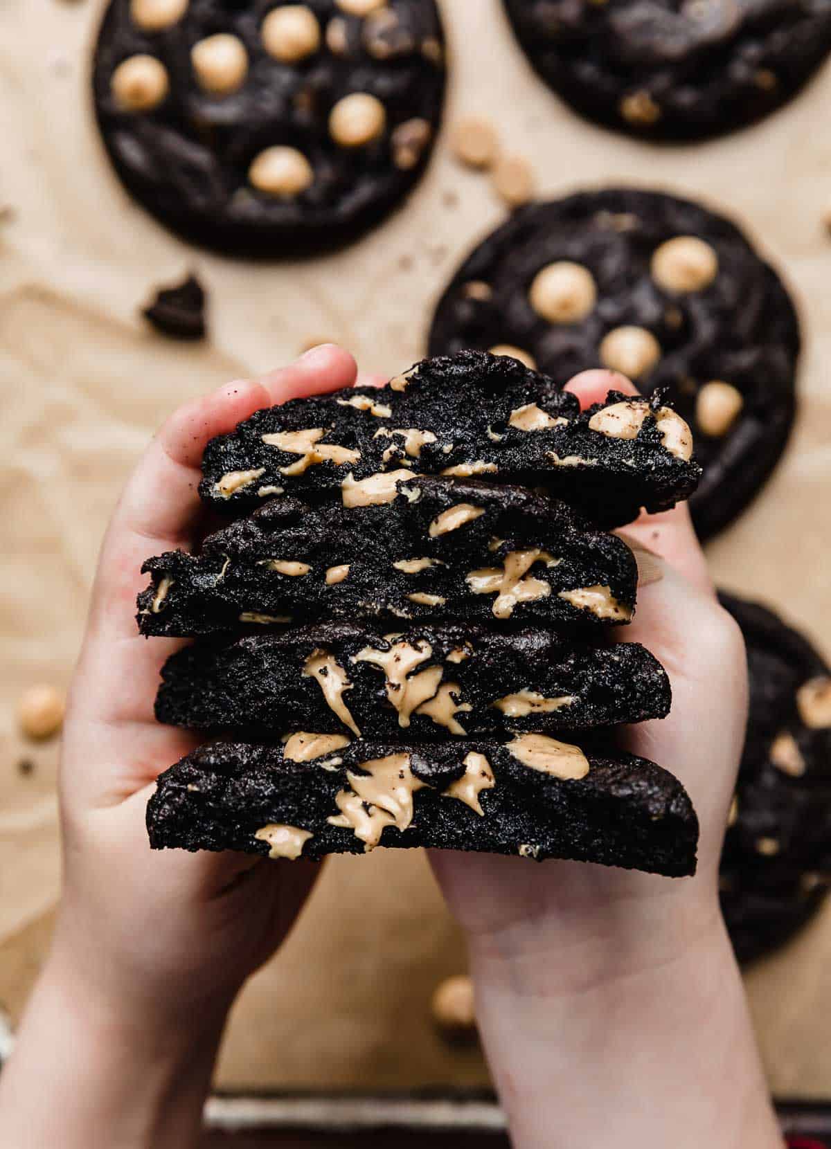 Two small hands holding a stack of Peanut Butter Oreo Cookies that have been cut in half.