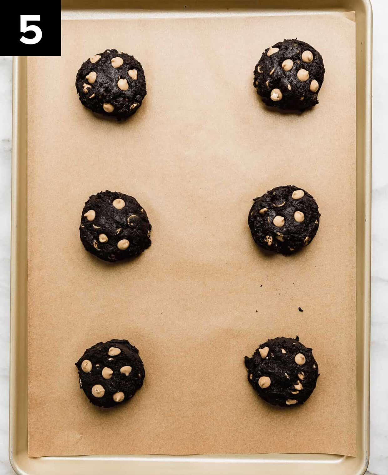 Oreo peanut butter cookie dough balls (6) on a Kraft lined baking sheet.