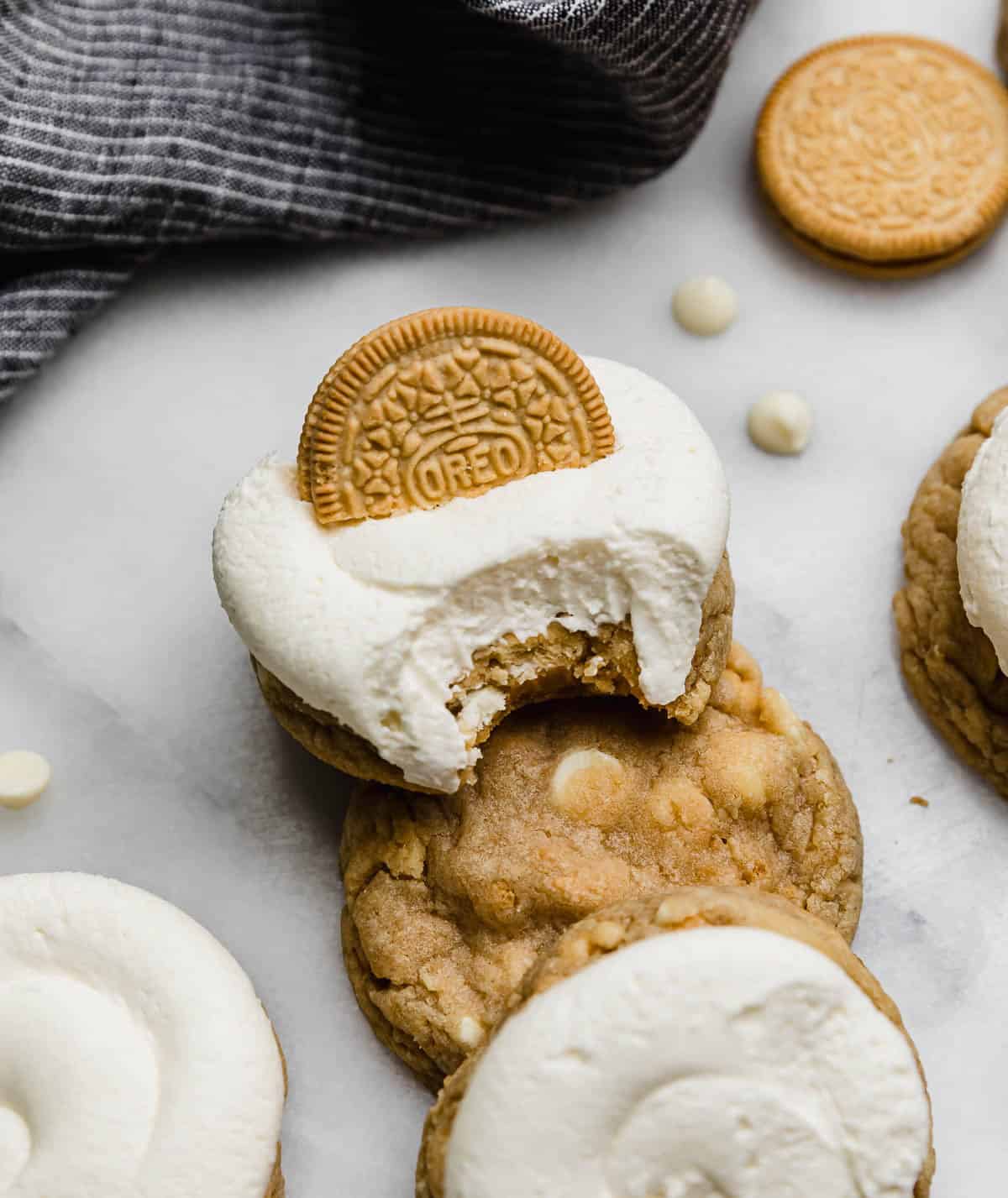 A Golden Oreo Cookie Recipe topped with a whipped cream cheese frosting and a bite taken out of the cookie.
