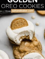 A bite taken out of a homemade golden oreo cookie with white chocolate chips, topped with a swirl of white frosting.