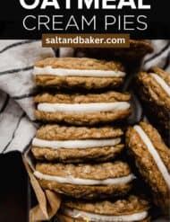 copy cat oatmeal creme pie cookies stacked close together on top of a striped linen napkin with the words, "oatmeal cream pies" written in white text above the photo.