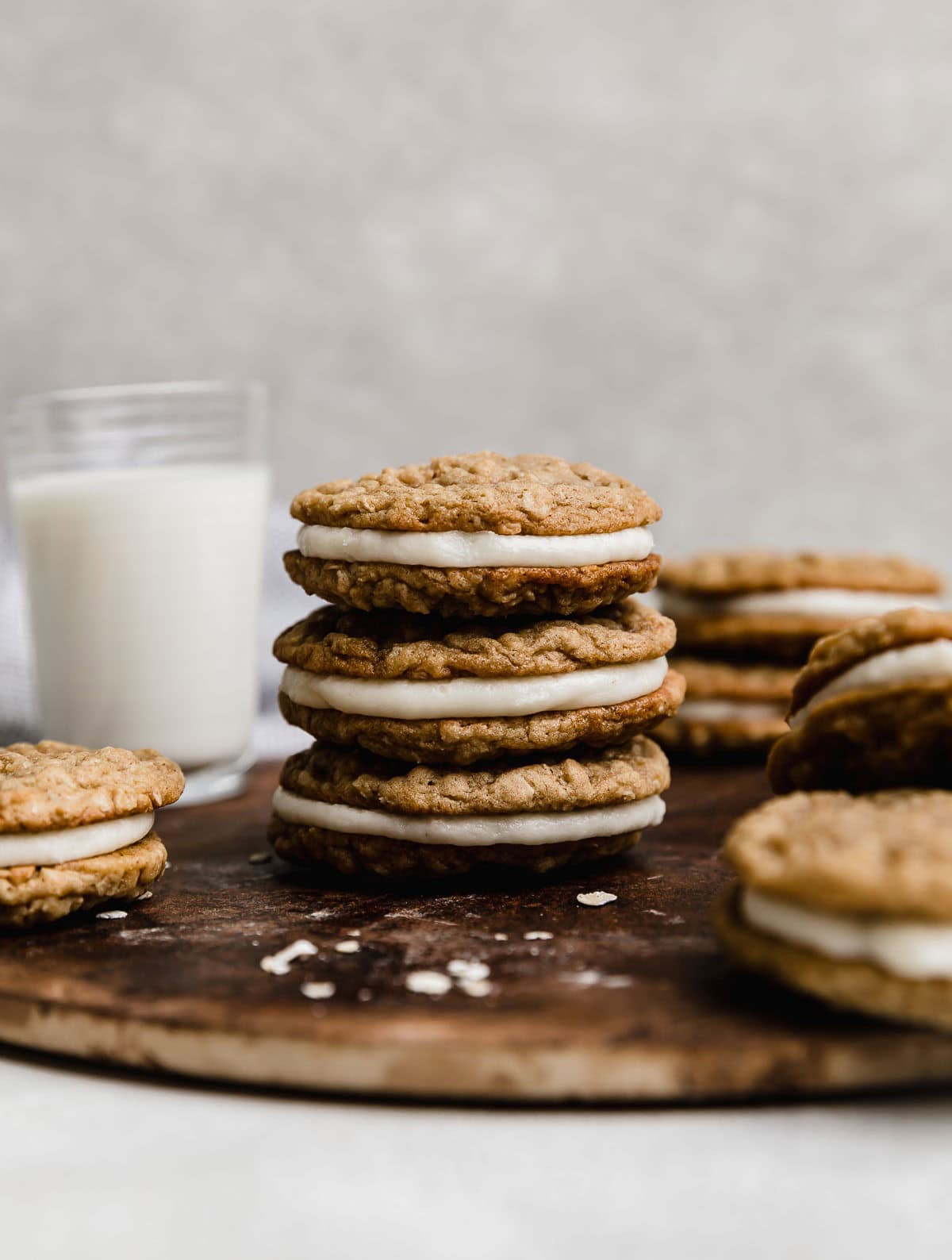 Three oatmeal creme pies stacked on top of each other with a glass of milk in the background.