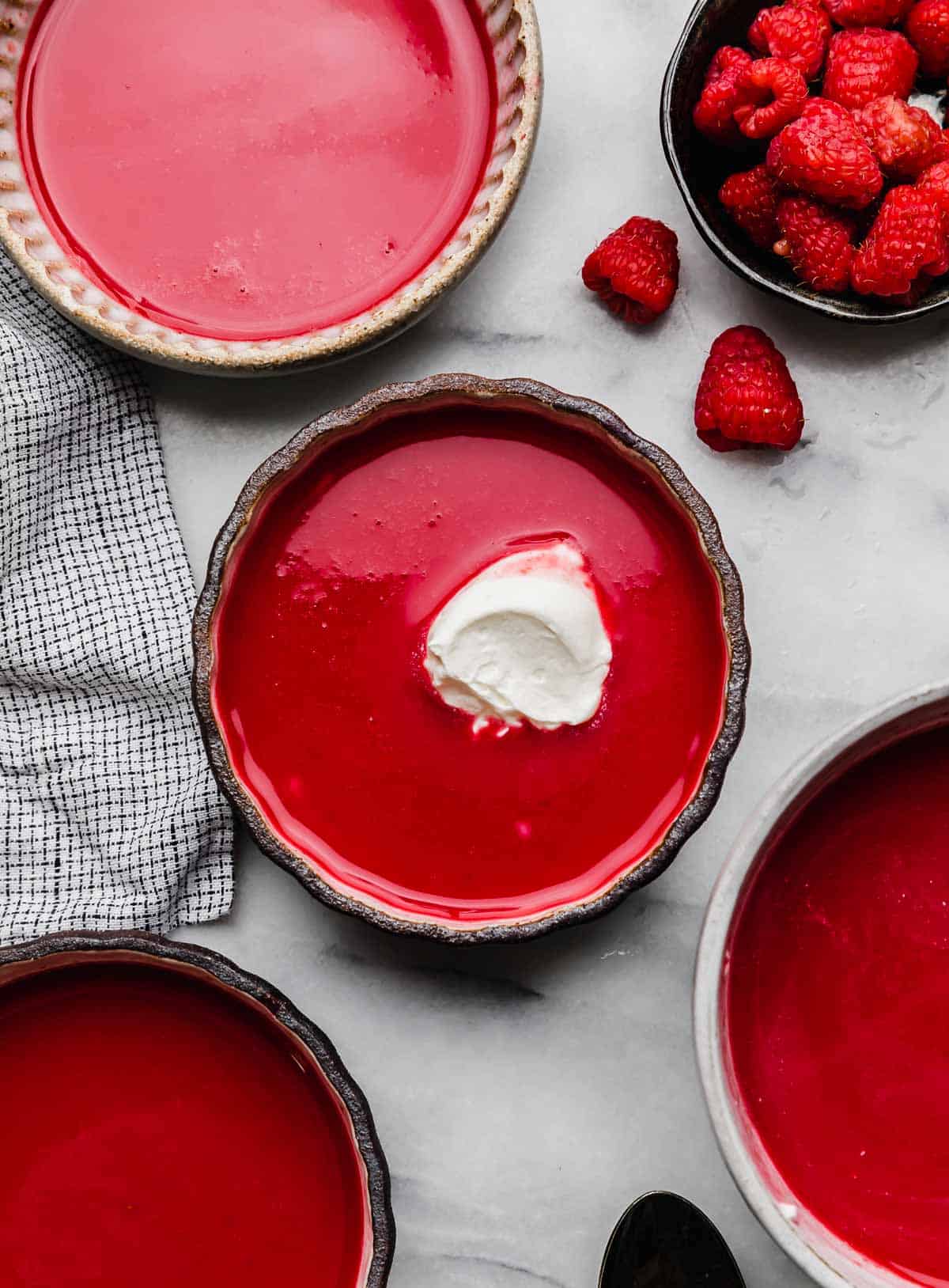 Dollop of whipped cream a top a chilled raspberry soup recipe on a white background.
