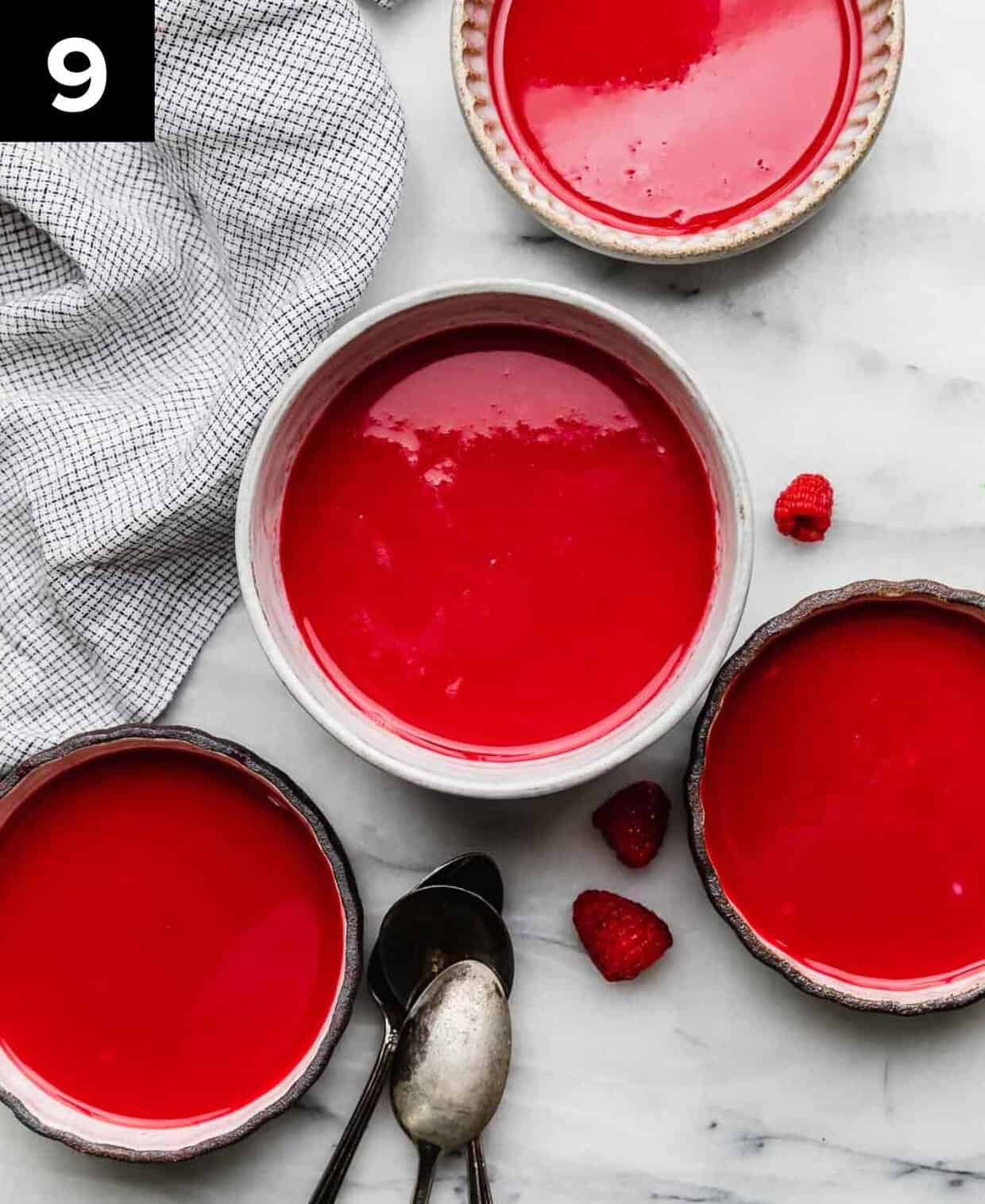 Four bowls filled with homemade Cold Raspberry Soup recipe on a white marble surface.