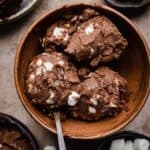 3 scoops of mini marshmallow and toasted almonds mixed into a chocolate custard ice cream base (rocky road ice cream), scooped into a brown bowl.