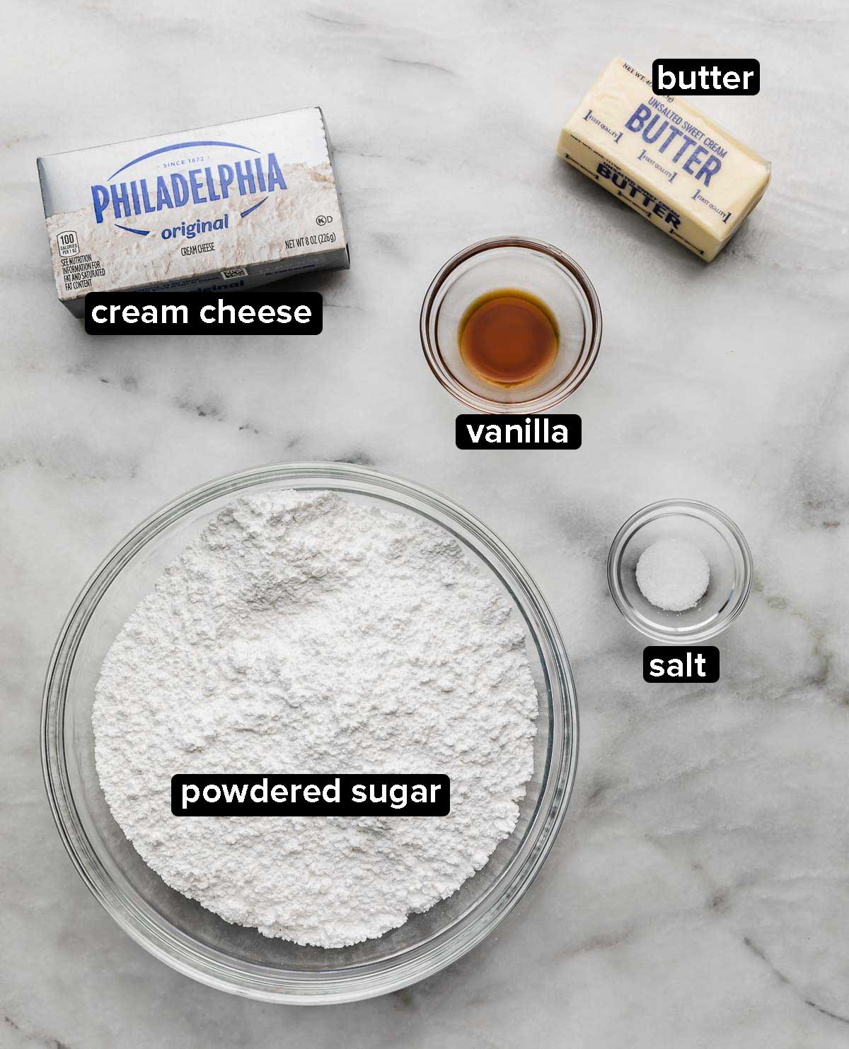 Brown Butter Cream Cheese Frosting ingredients on a white and gray marble surface: powdered sugar, cream cheese, vanilla, butter, salt.