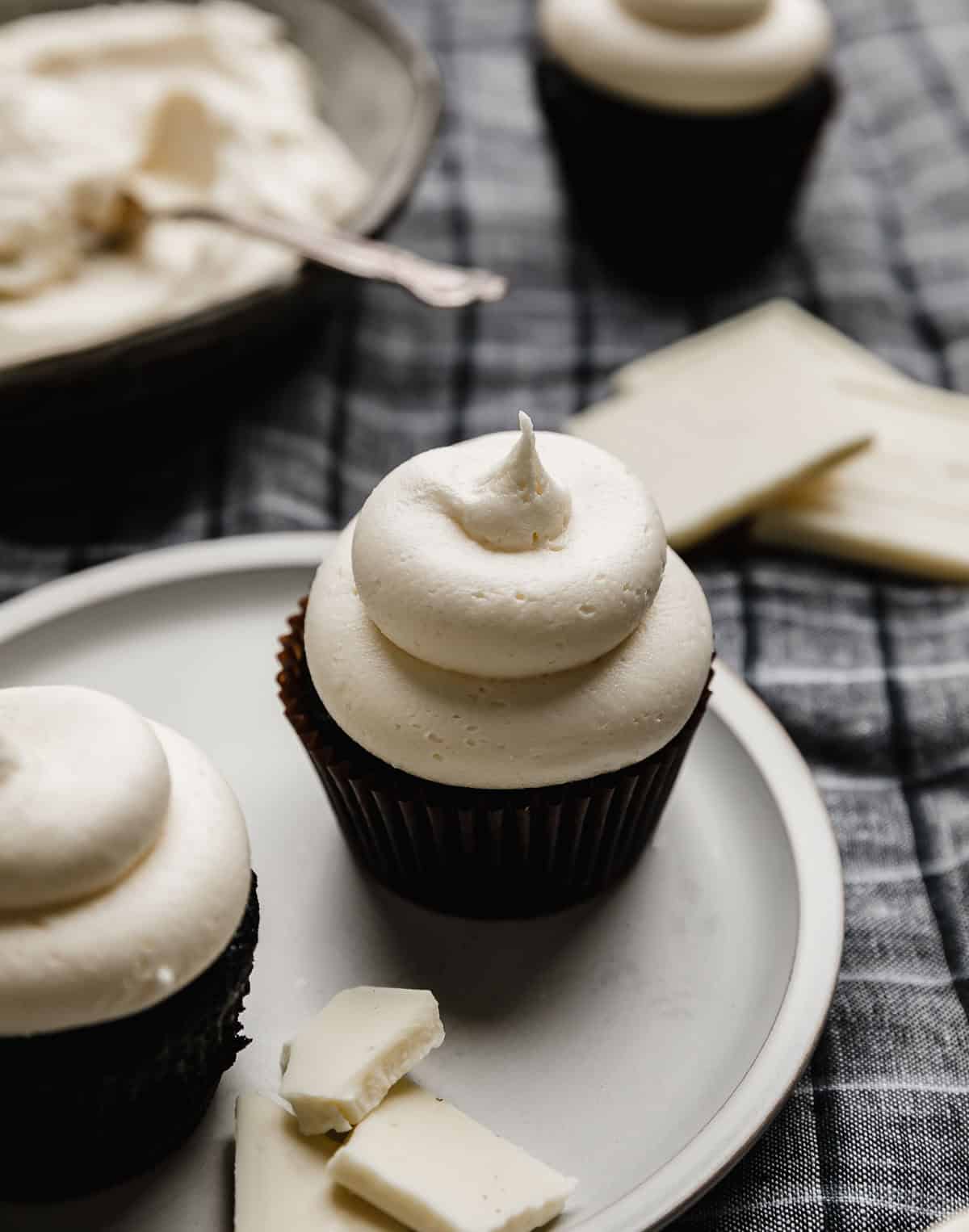 A swirl of White Chocolate Buttercream Frosting on a black cupcake.