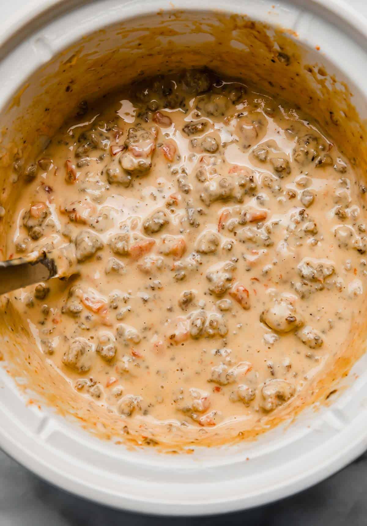 Overhead photo of Cream Cheese Sausage Rotel Dip in a white crock pot.